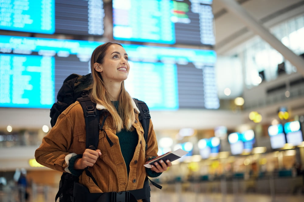 fata in aeroport cu bilet de avion si pasaport in mana